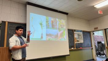 A photo of a man in front of a classroom giving a presentation