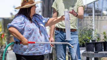AIR team member Dean Watson and an intertribal nursery member holding a graduated cylinder and watering wand